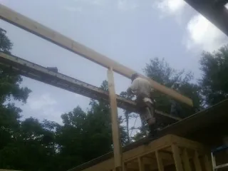 Carpenter setting a ridge beam over a new addition frame — Ice Dam Removal by Roofing Brothers in Fertile