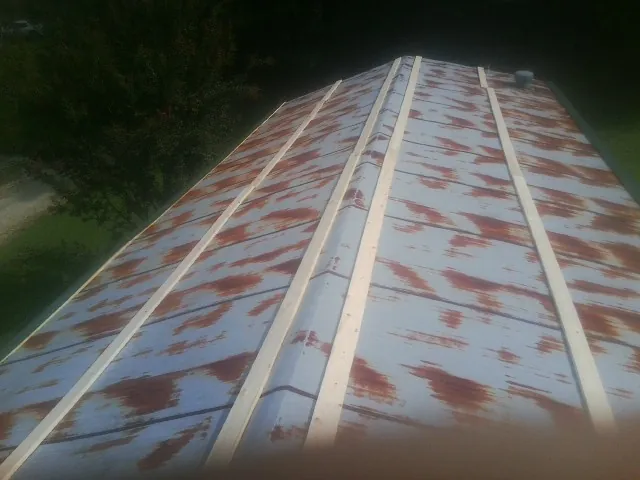 Rusted metal roof panels with new wood purlins before replacement — Storm Damage Roof Repair in Fertile by Roofing Brothers
