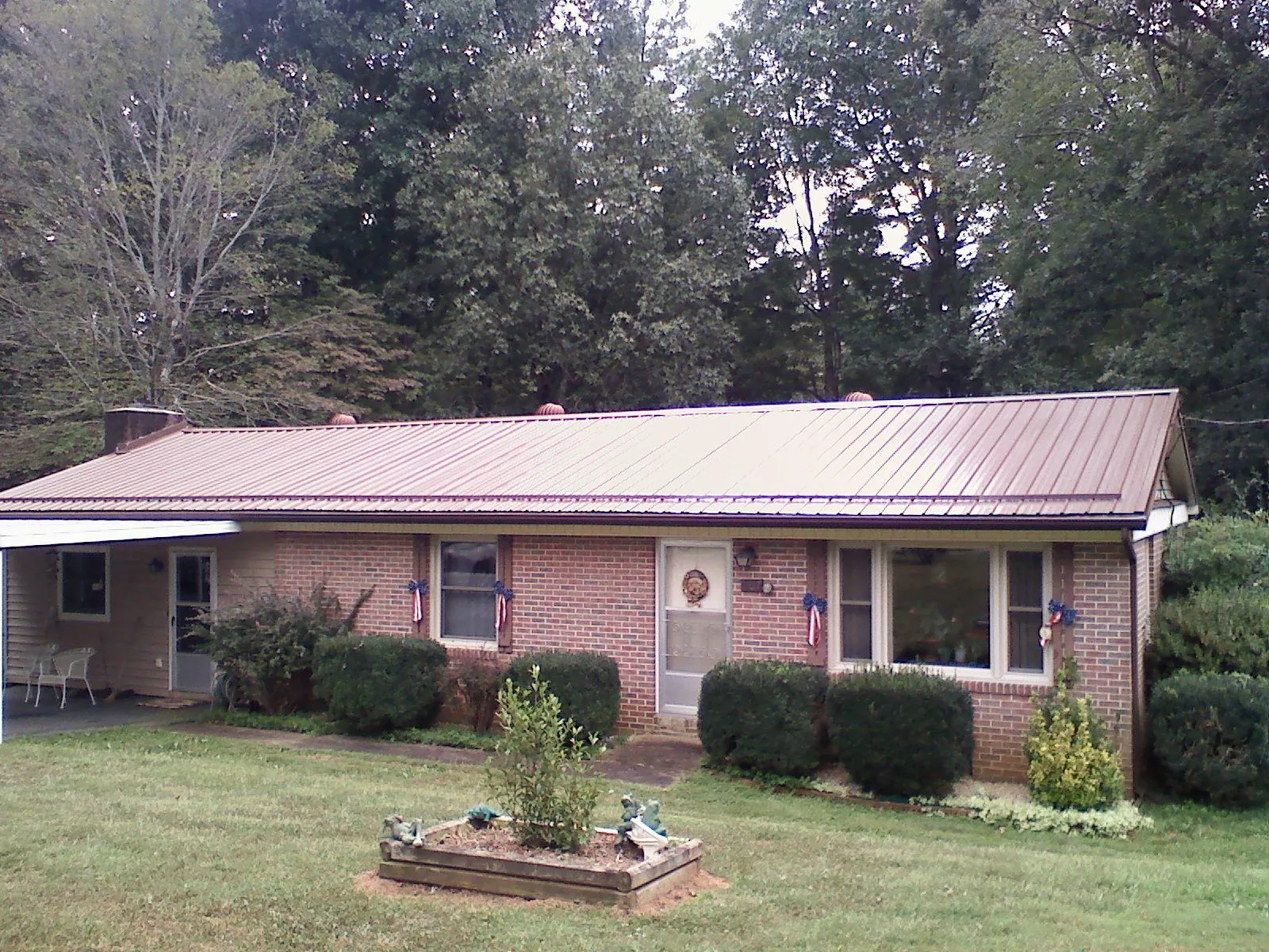 Bronze metal roof on a brick ranch home with a carport in Fertile