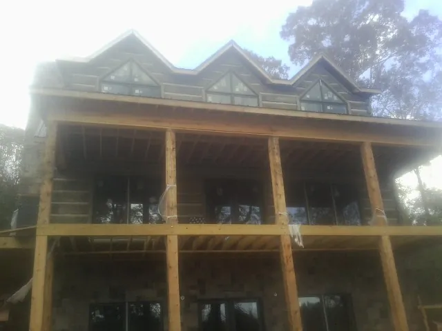 Dormers and porch framing on a large log home under construction — Roof Coating work by our crew in Fertile