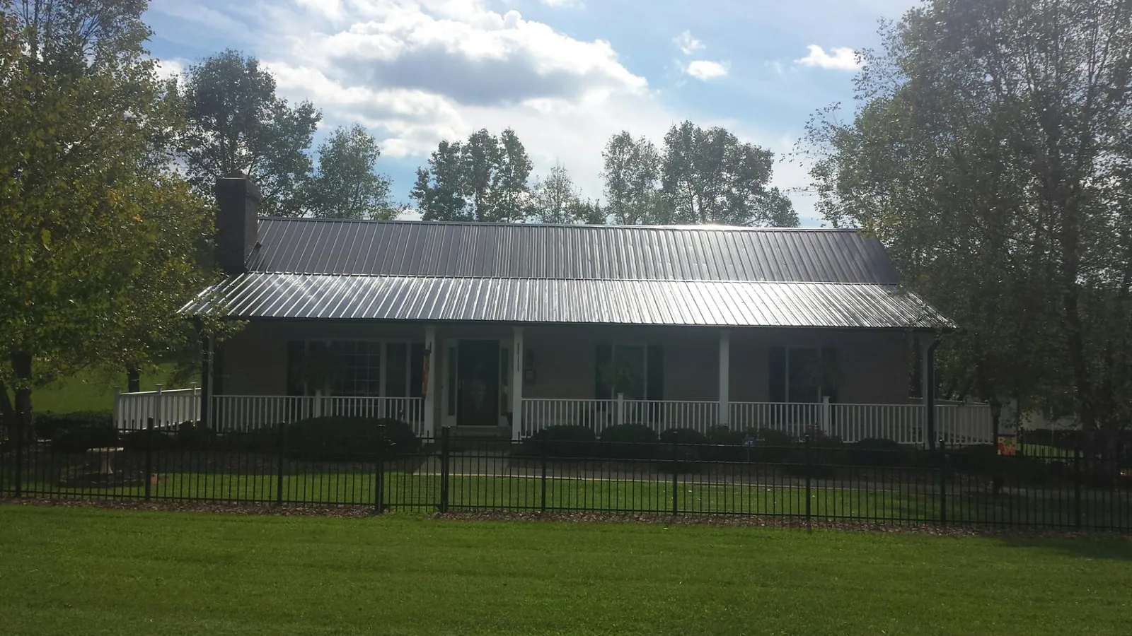 Gray metal roof on a brick ranch with a full width front porch — Gutter Guard Installation work by our crew in Fertile