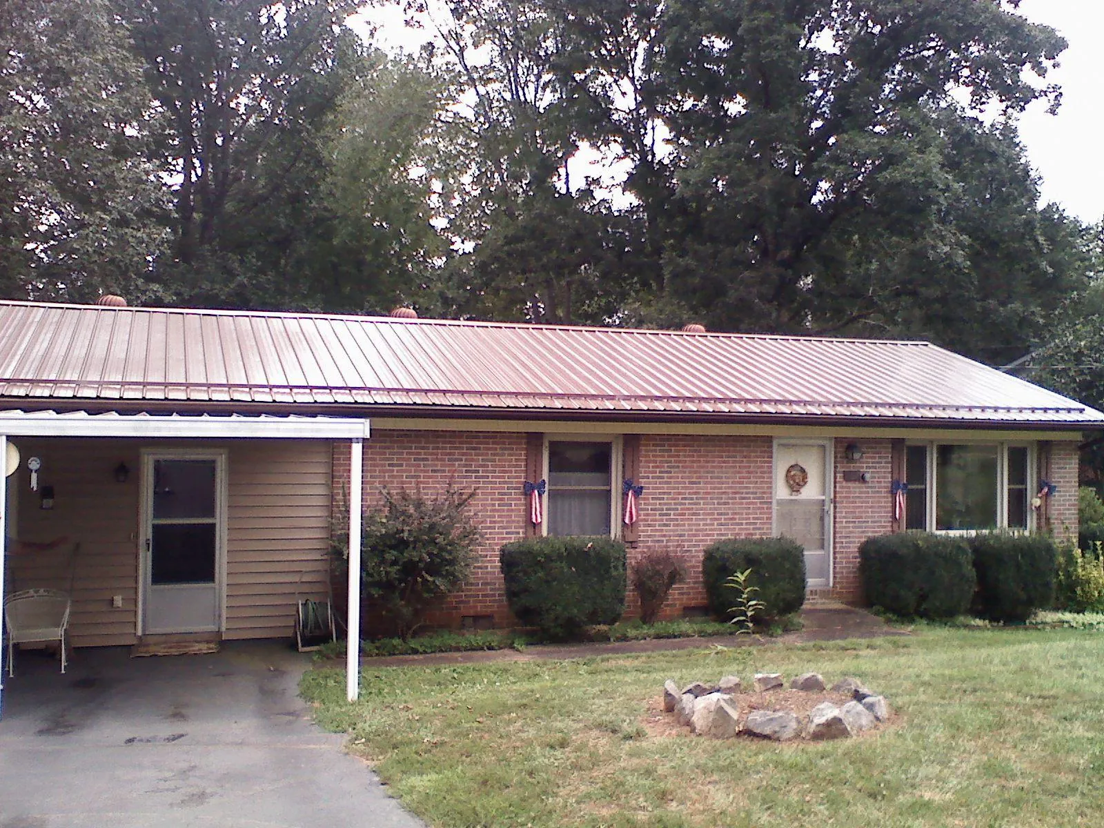 Bronze metal roof and carport on a brick ranch home — Roof Repair work by our crew in Fertile