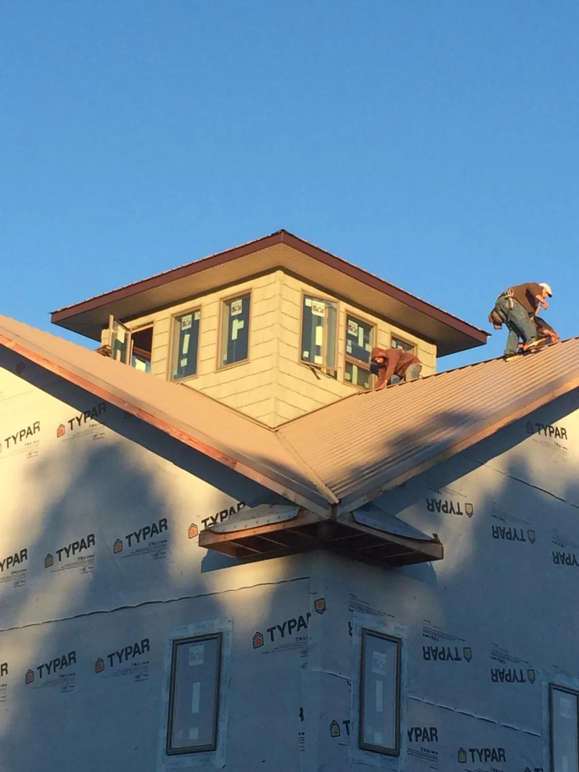 Roofers working around a rooftop cupola on a new metal roof at sunset — Roof Waterproofing in Fertile by Roofing Brothers